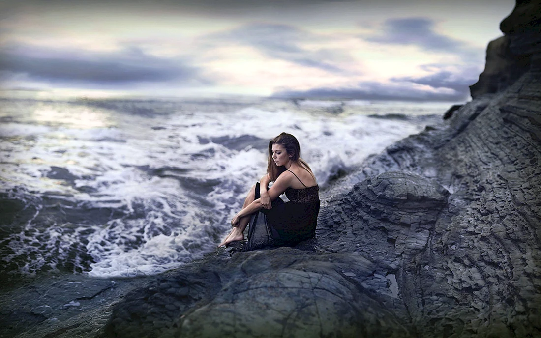 Девушка сидит на берегу моря
