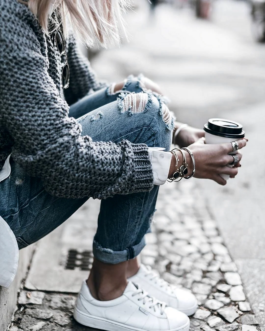 Девушка в рваных джинсах с кофе