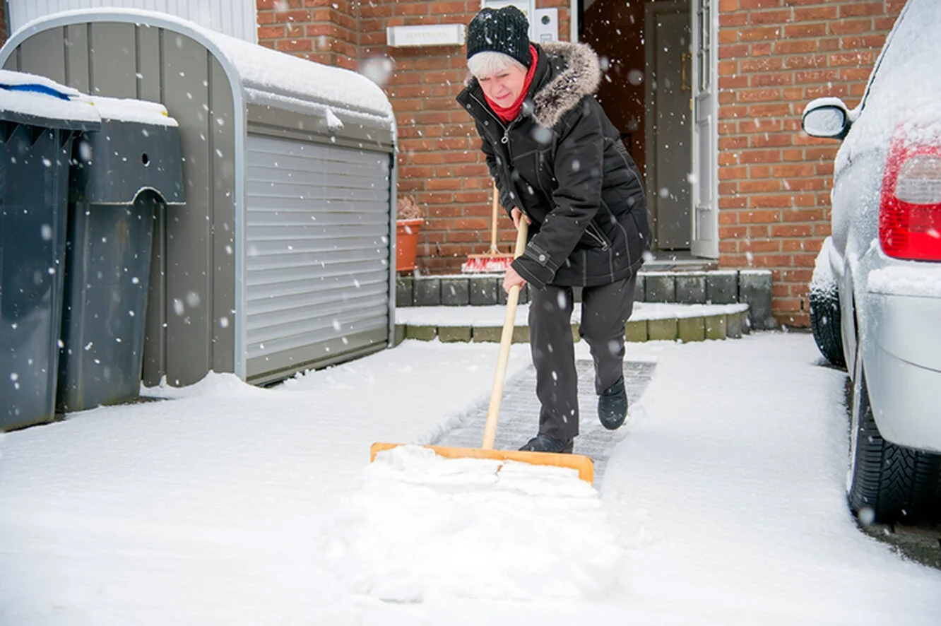 Женщина убирает снег лопатой